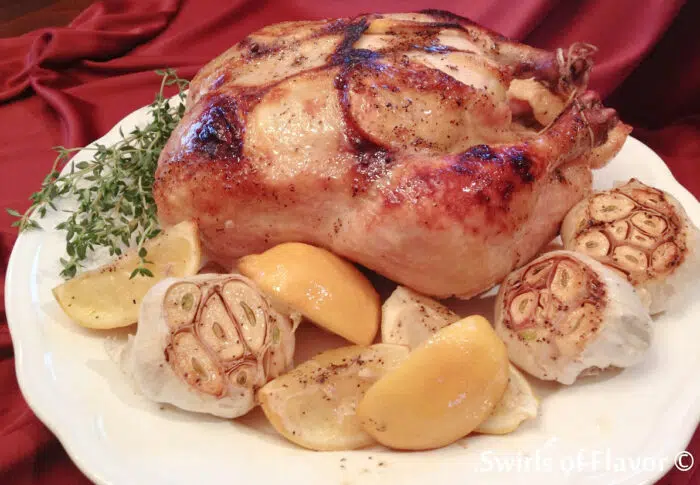 roasted chicken with lemons and garlic on platter