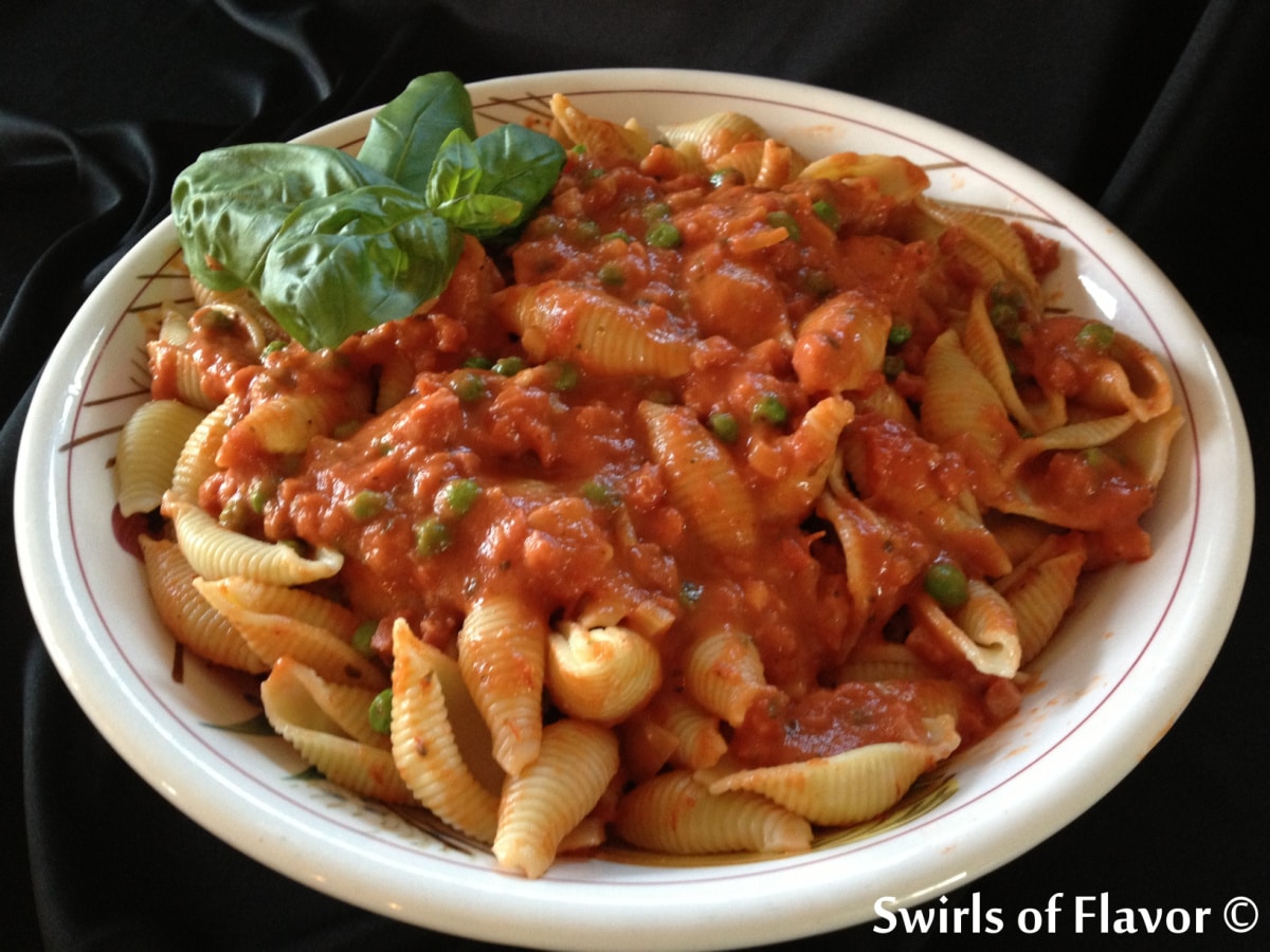 pasta with vodka sauce proscuitto and peas in a white dish