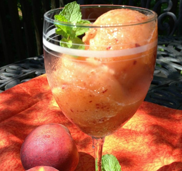 peach sorbet in a wine glass with fresh mint