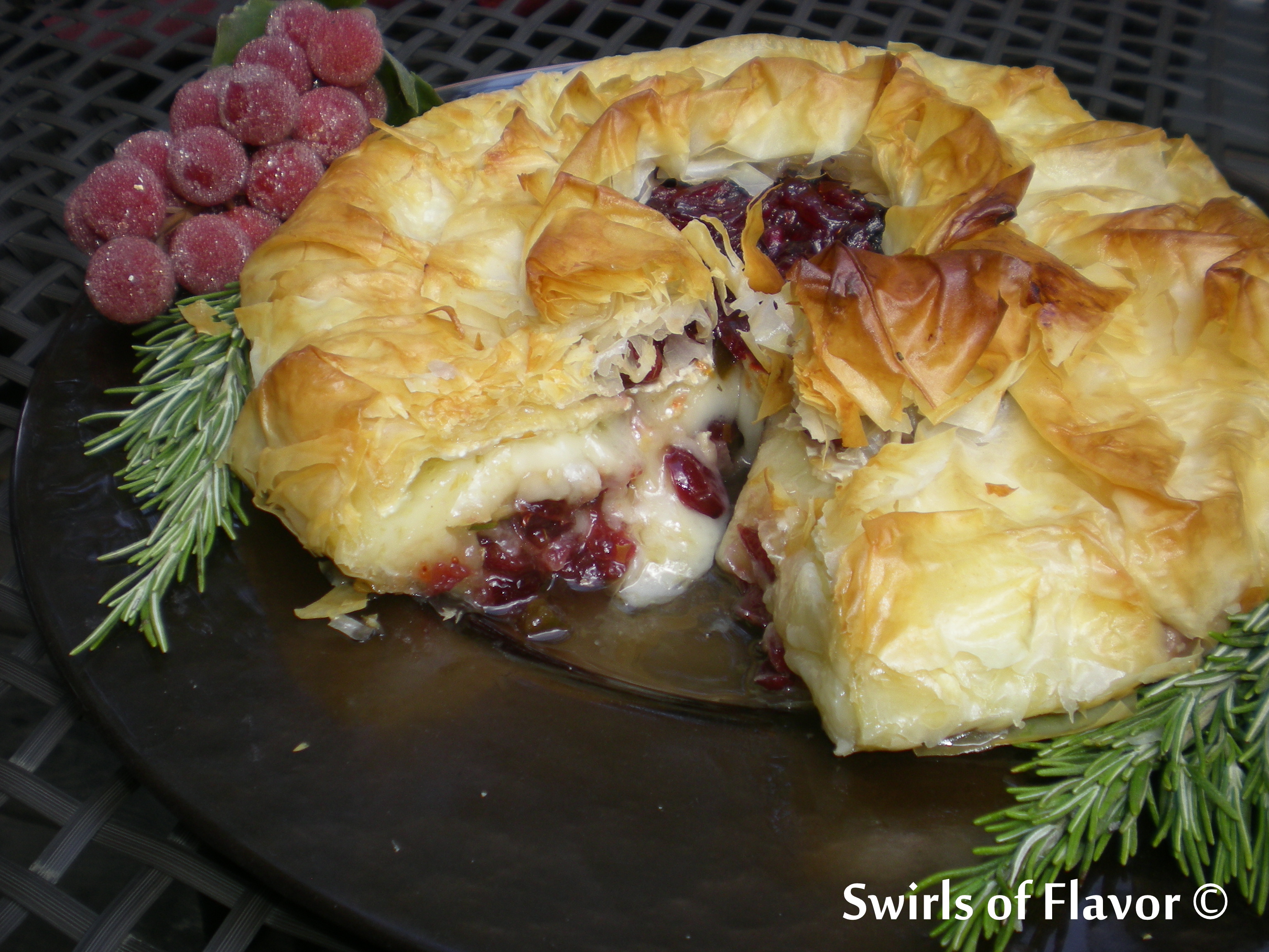 Phyllo Wrapped Brandied Cranberry Baked Brie is an easy recipe of phyllo dough layers surrounding a cranberry brandy topped Brie accented with a hint of rosemary and Dijon and a touch of spice. This holiday appetizer recipe will impress your guests for sure! #bakedbrie #brandy #cranberry #phyllodough #appetizer #holiday #Thanksgiving #swirlsofflavor