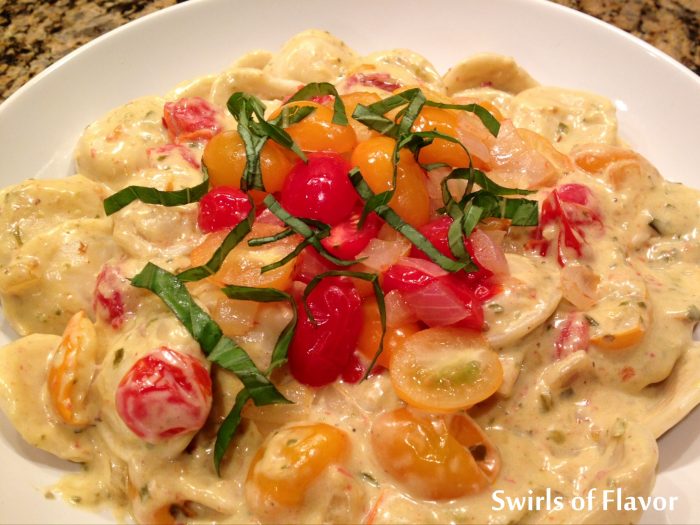 Creamy Pesto Ravioli is an easy recipe for dinner tonight. Alfredo sauce, pesto and white wine combine to form a flavorful creamy sauce that coats mini cheese ravioli and fresh tomatoes.