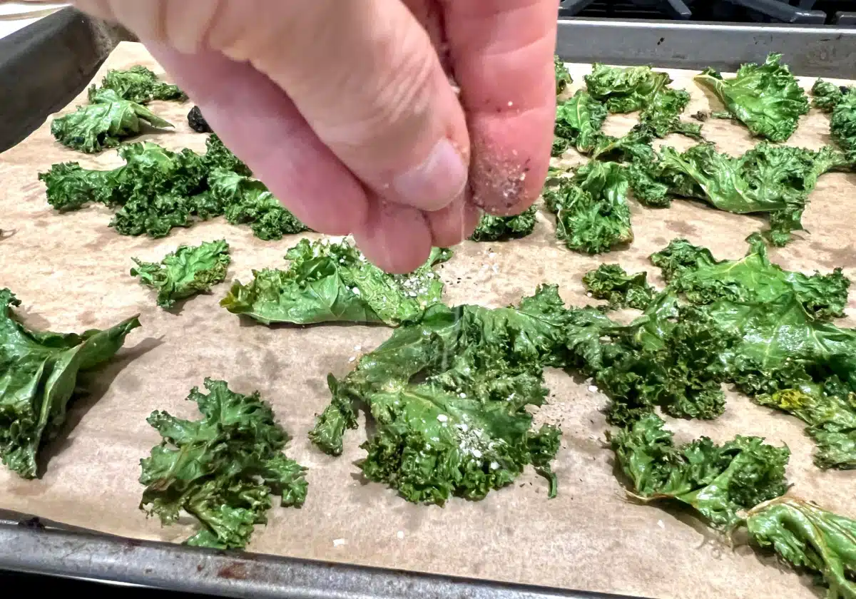 sprnkling kale leaves with seasonings