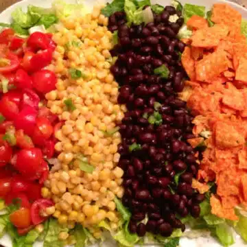 mexicali salad with tomatoes, black beans, corn and chips on top