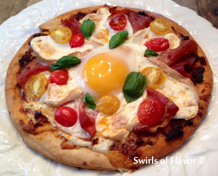 Smoked Mozzarella & Prosciutto Breakfast Pizzas are made with store bought pizza crusts topped with pesto, prosciutto, smoked mozzarella and tomatoes, then with an egg. and baked in the oven! easy recipe | baked pizza | breakfast | Mother's Day | fun for kids | store bought pizza crust | #swirlsofflavor