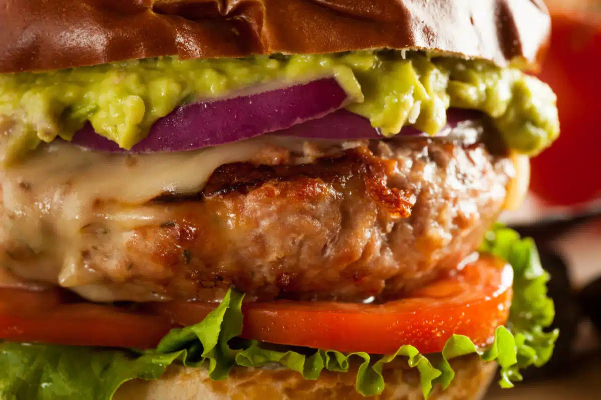 closse up of turkey burger with tomato, lettuce and red onion