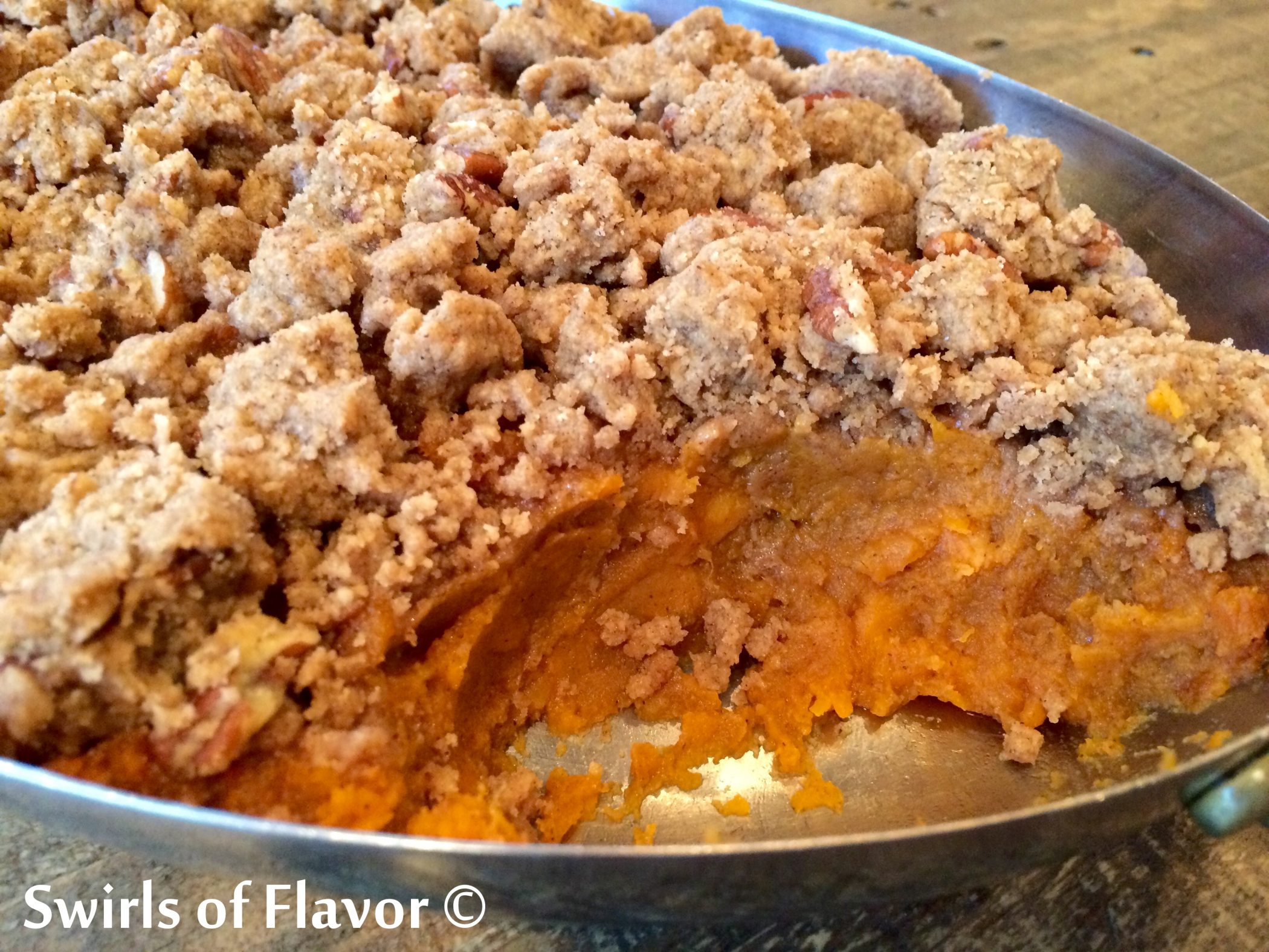sweet potatoes casserole with pecans in baking dish with scoop out