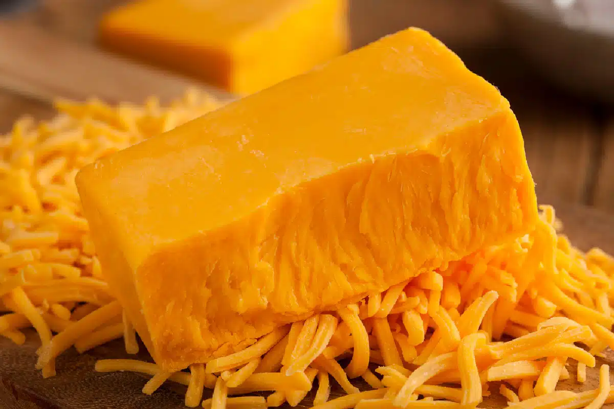 a block of cheddar cheese partially shrdded