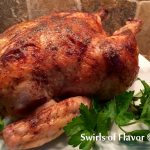 roasted chicken on platter with gravy and fresh parsley