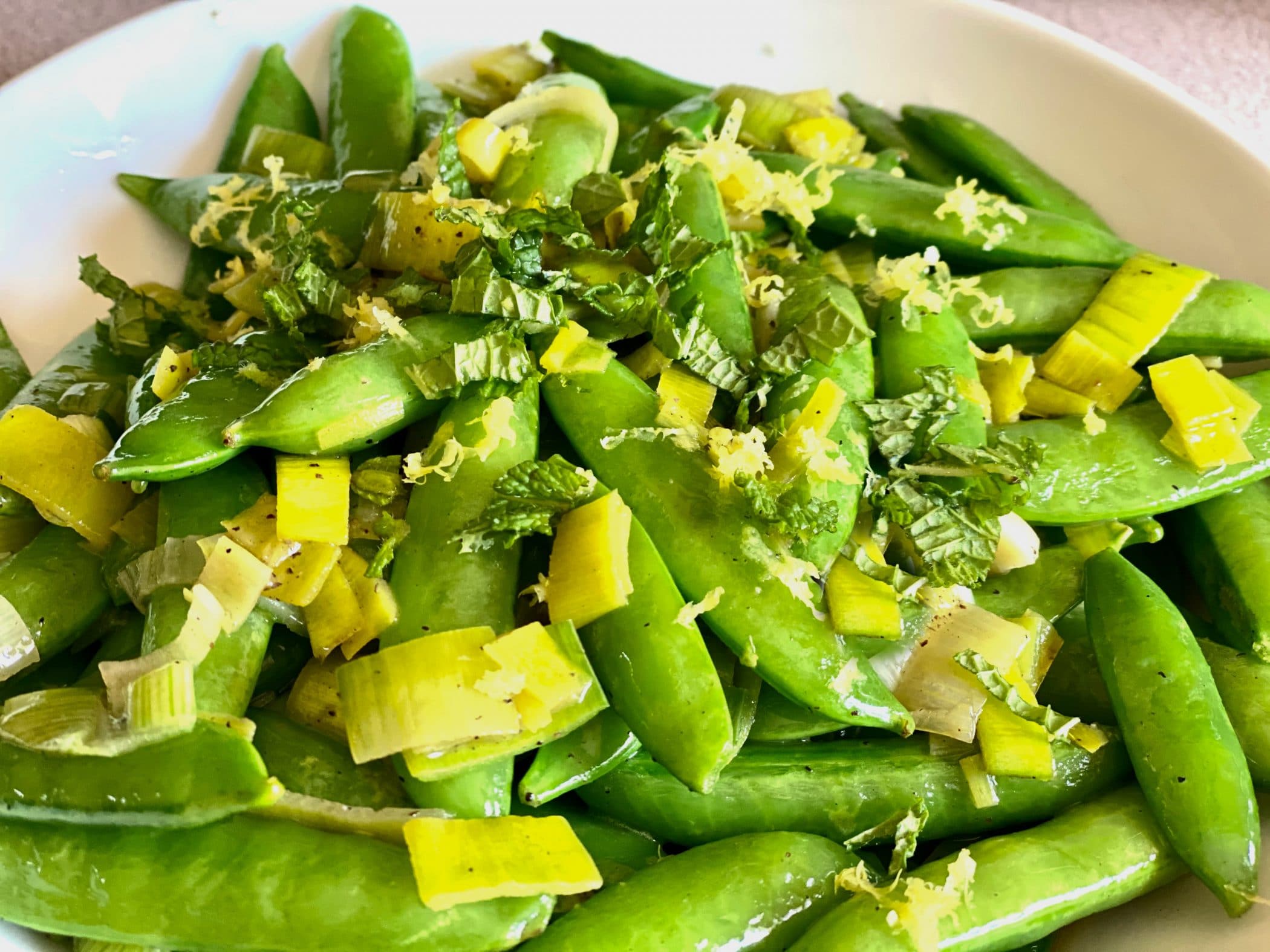 close up photo of sugar snap peas with fresh mint and lemon zest