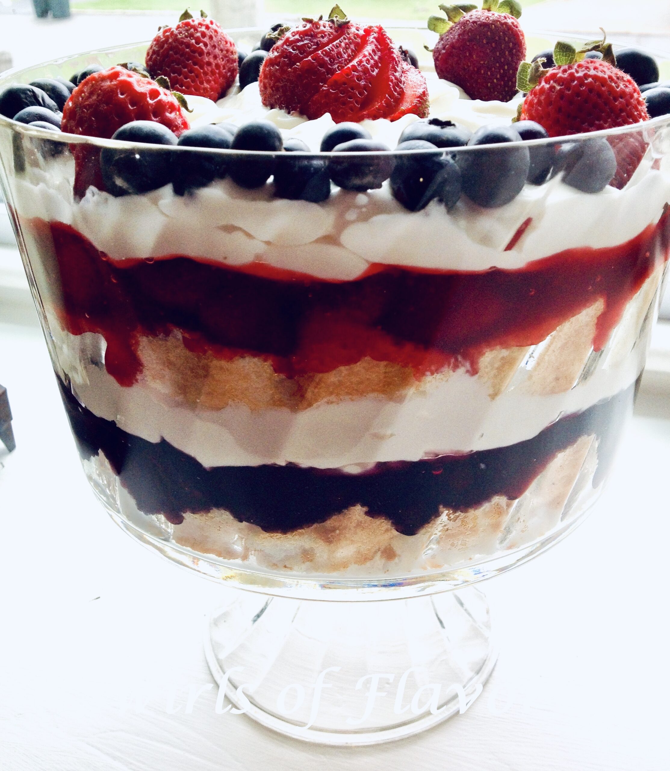 Side view of a mixed berry trifle in clear pedestal bowl