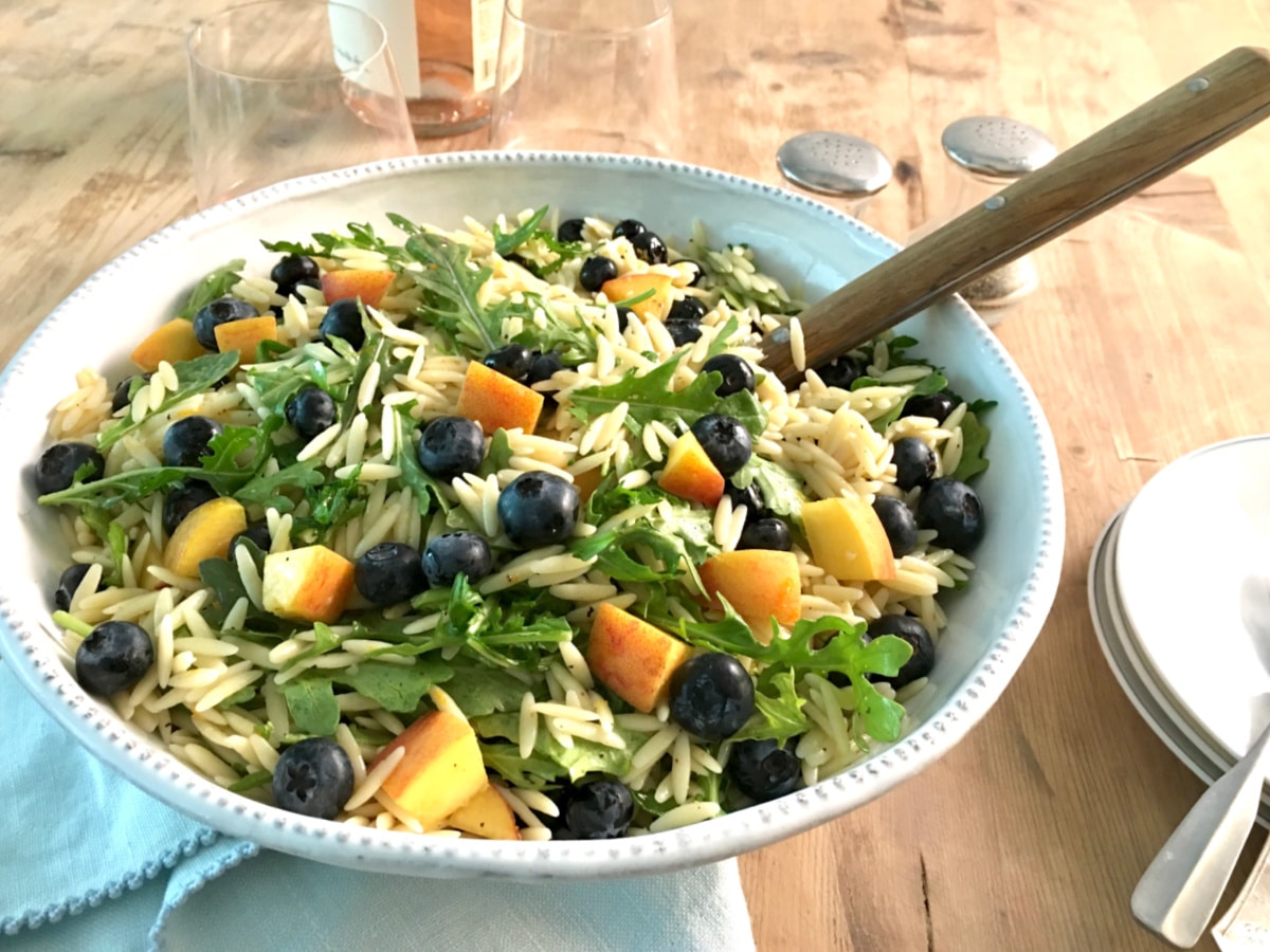 blueberry peach orzo salad in bowl with wooden spoon