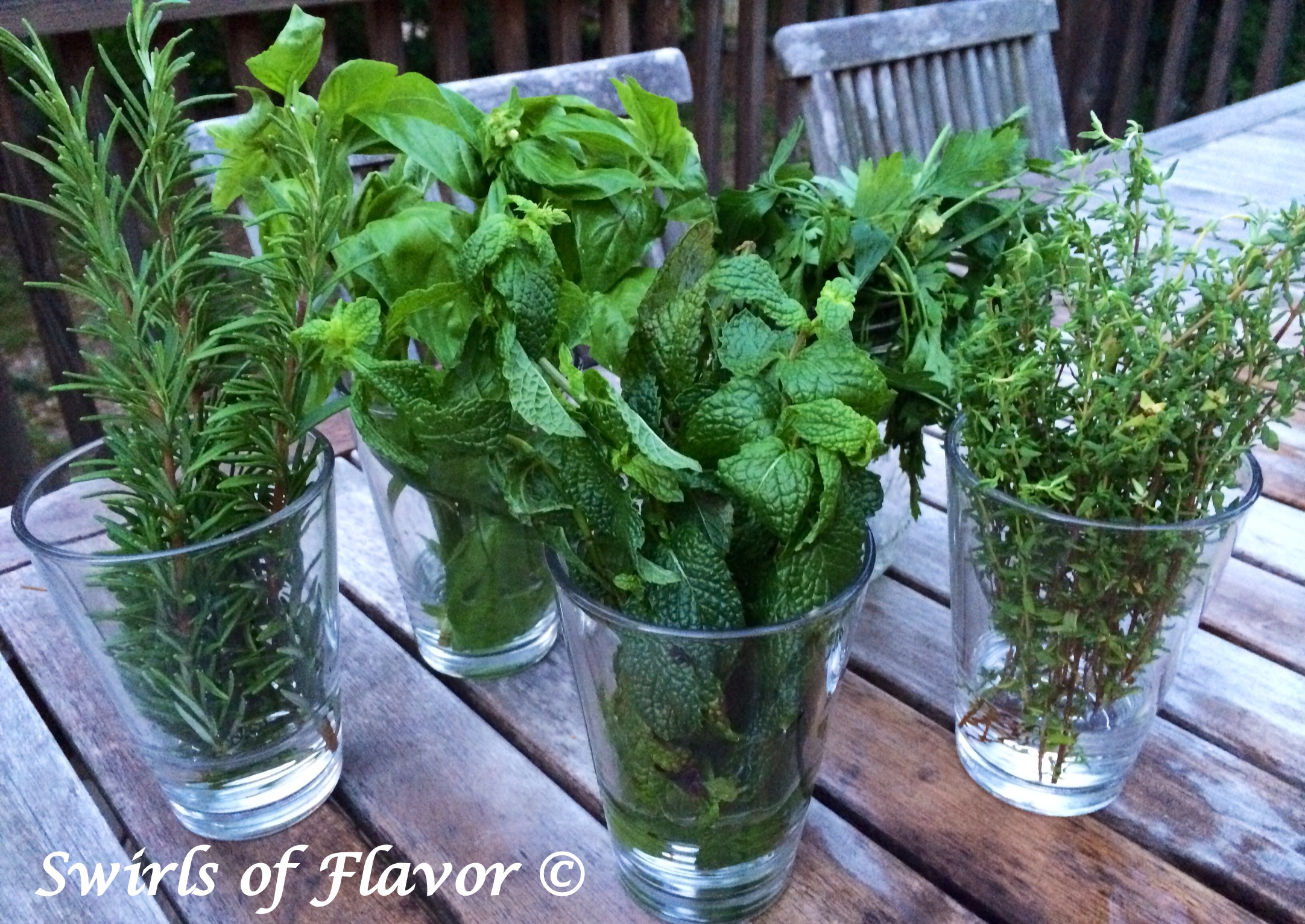 Fresh herbs in glasses on a wooden table