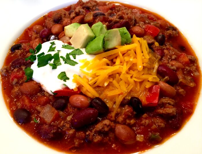 bowl of been and ground beef chili with toppings