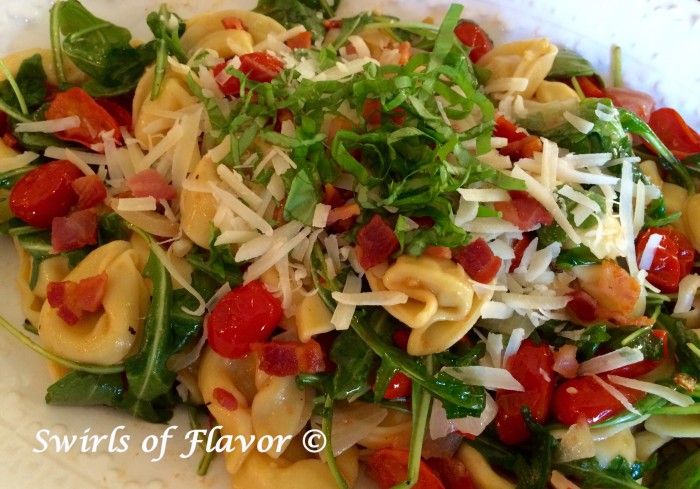 Tortellini pasta with pancetta and tomatoes and thinly sliced fresh basil on top