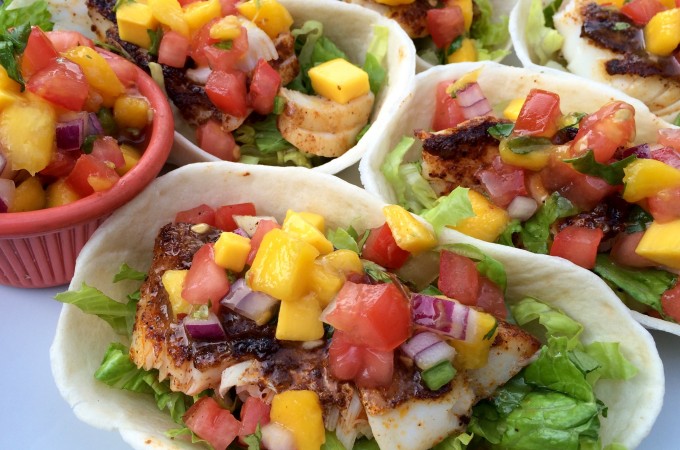 It's Taco Tuesday! Season and grill your favorite fish, top with a fresh Mango Pico De Gallo and your Fish Tacos With Mango Pico De Gallo will be bursting with tropical flavors! #fish #fishtacos #mango #picodegallo #homemade #tacotuesday #easyrecipe #dinner #swirlsofflavor
