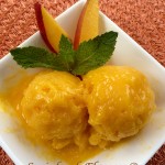 Two scoops of mango sorbet with mango slices and fresh mint in white dish