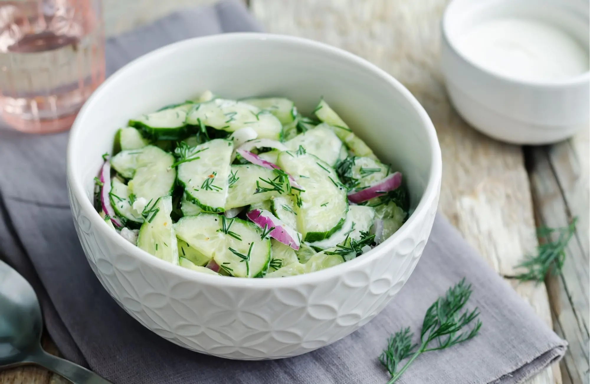 creamy cucumber onion salad with dill in white bowl