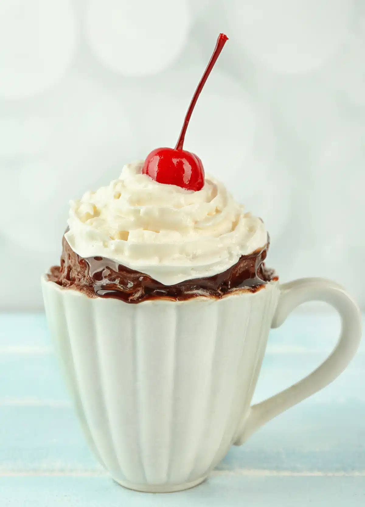 hot chocolate mug cake with whipped cream and a cherry on top