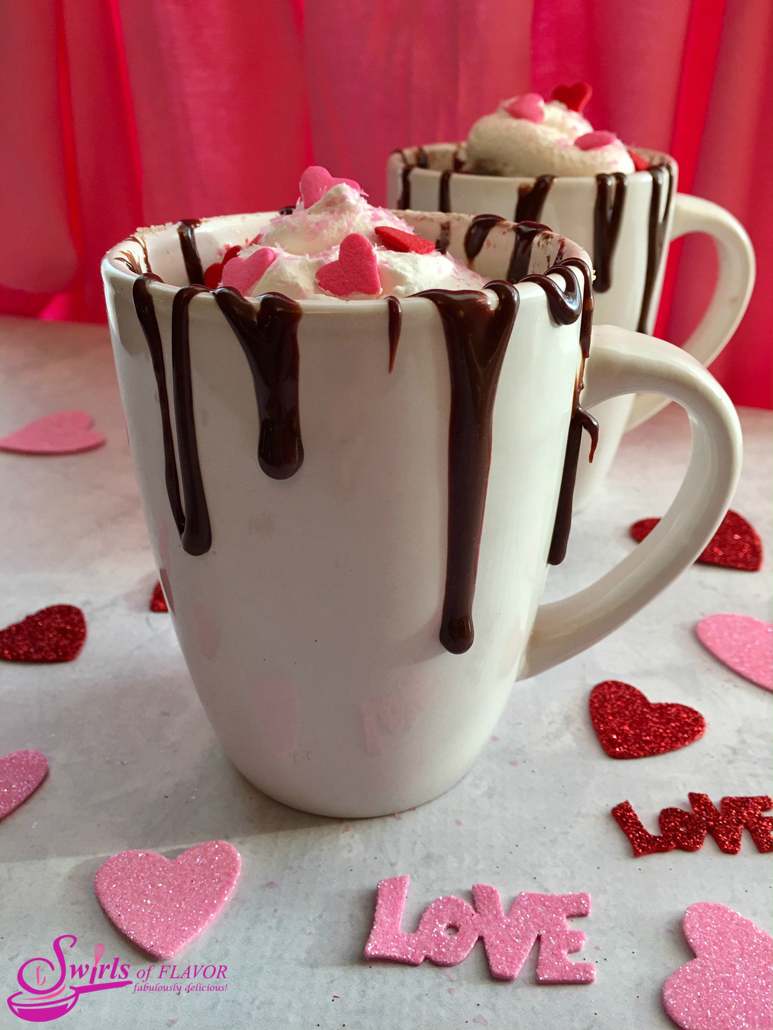 two mugs filled with a chocolate mug cake recipe and topped with fudge and whipped topping
