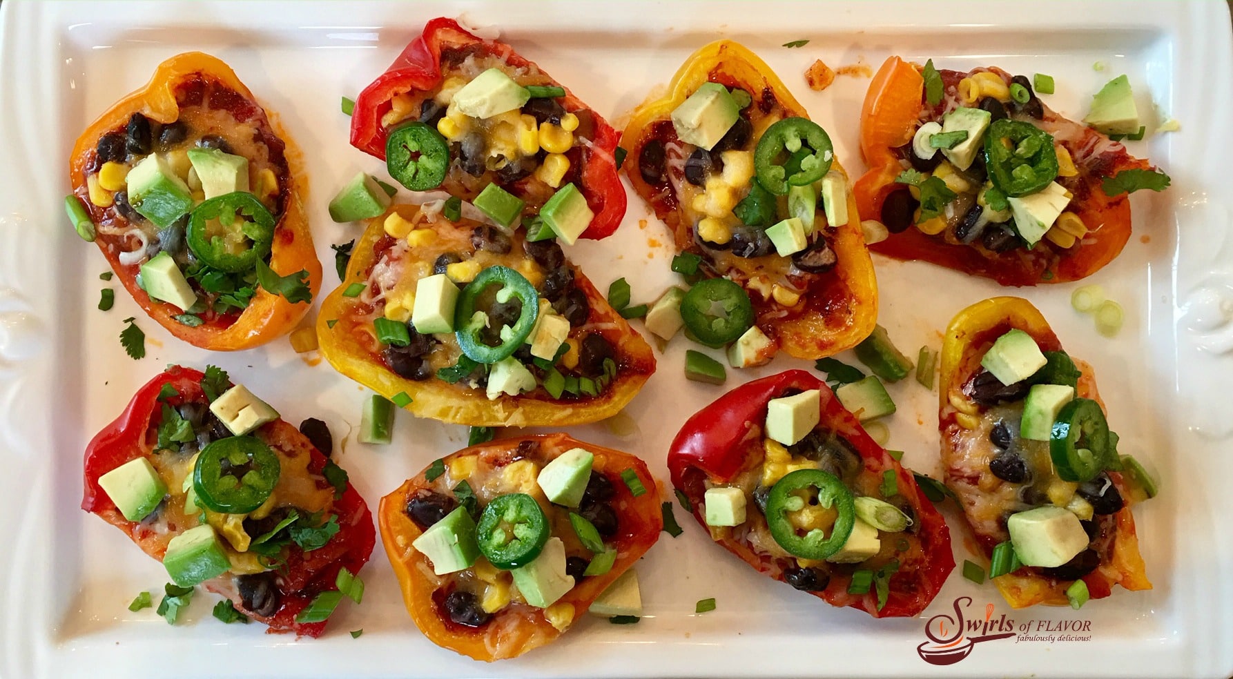 Spicy Nacho Stuffed Peppers are seasoned with taco seasoning and brimming with salsa, black beans, corn, avocado, jalapeno and cheesy goodness! #nachos #easyrecipe #appetizer #nachosrecipe #lowfat #glutenfree #cheese #stuffedpeppers #swirlsofflavor