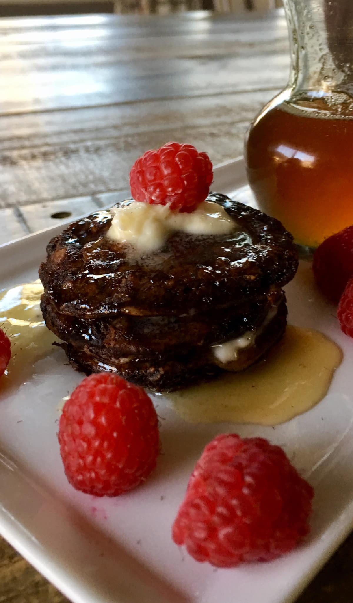 chocolate pancakes on a white plate with raspberries