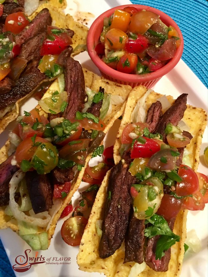 Seasoned slices of juicy skirt steak are nestled in a crunchy corn shell and topped with a lime-scented fresh heirloom tomato salsa. tacos, Taco Tuesday, steak tacos, Cinco de Mayo, grilling, fresh salsa