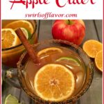 cup of warm apple cider with orange slices and text overlay
