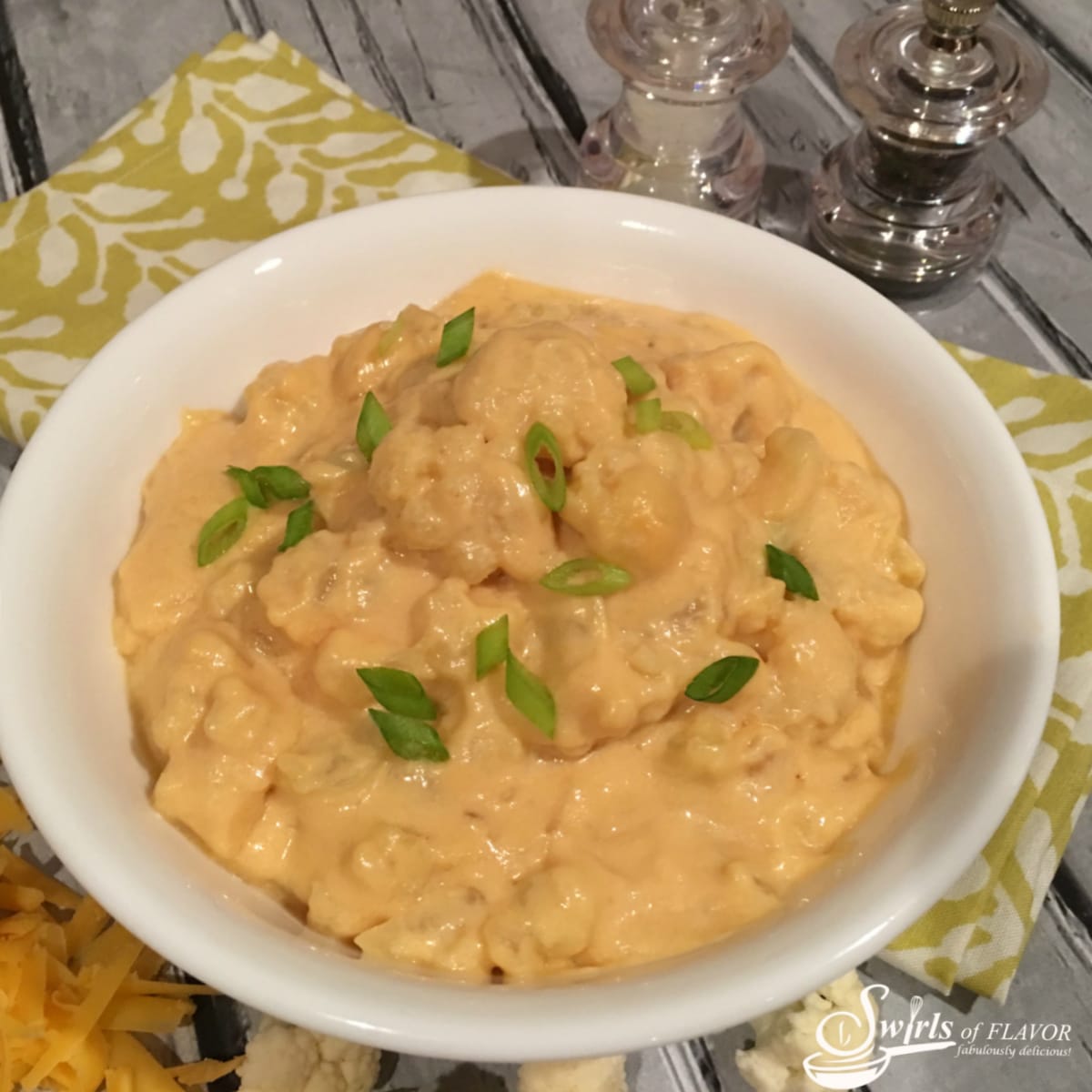 cauliflower macaroni and cheese with sliced scallions in a white bowl