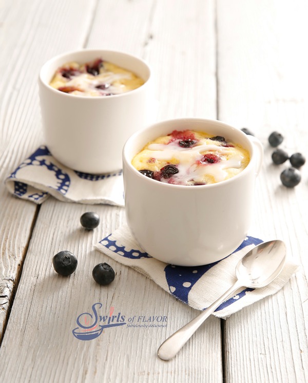 blueberry mug cake recipe with lemon glaze in two mugs with spoon