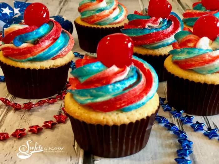 4th of July cupcakes are simple from-scratch vanilla cupcakes topped with a homemade buttercream frosting decorated with red and blue stripes and topped with a cherry. Perfect for your patriotic celebration!