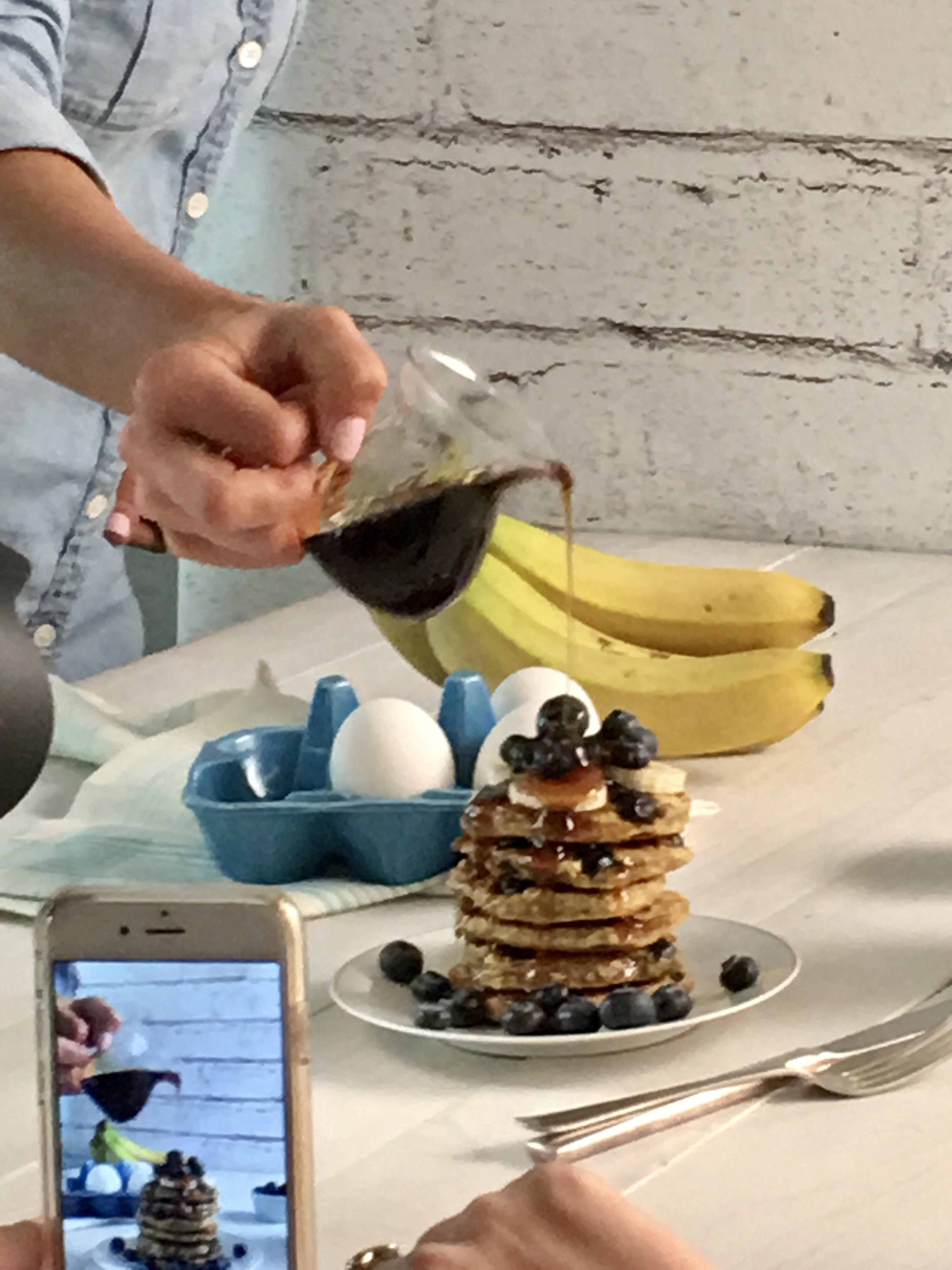 Action shot of pouring syrup over Gluten Free Blueberry Pancakes at photo shoot.