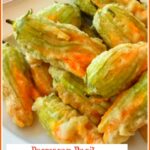 Cheese stuffed squash blossoms in a light fried batter on a round plate
