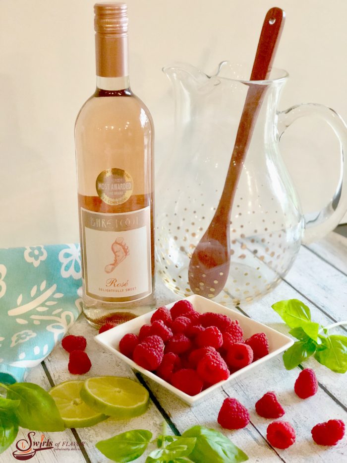 Basil Raspberry Rose Sangria is bursting with juicy raspberries, fresh basil, lime, Rose wine, vodka, raspberry liqueur and seltzer for a light fruity summertime sangria. #easyrecipe #summersangria #cocktails #drinks #rosesangria #sangria #rosewine #raspberries #basil #lime #vodka #raspberryliqueur #happyhour #swirlsofflavor