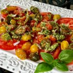 Pesto Tomato Salad is an easy 4 ingredient recipe. Garden fresh tomatoes and red onion are tossed in a homemade pesto transforming juicy tomatoes into a recipe that's bursting with fresh flavor and summertime goodness. #salad #tomato #tomatosalad #pesto #threeingredientrecipe #easyrecipe #summer #farmersmarket #heirloomtomatoes #vineripenedtomatoes #sidedish #swirlsofflavor