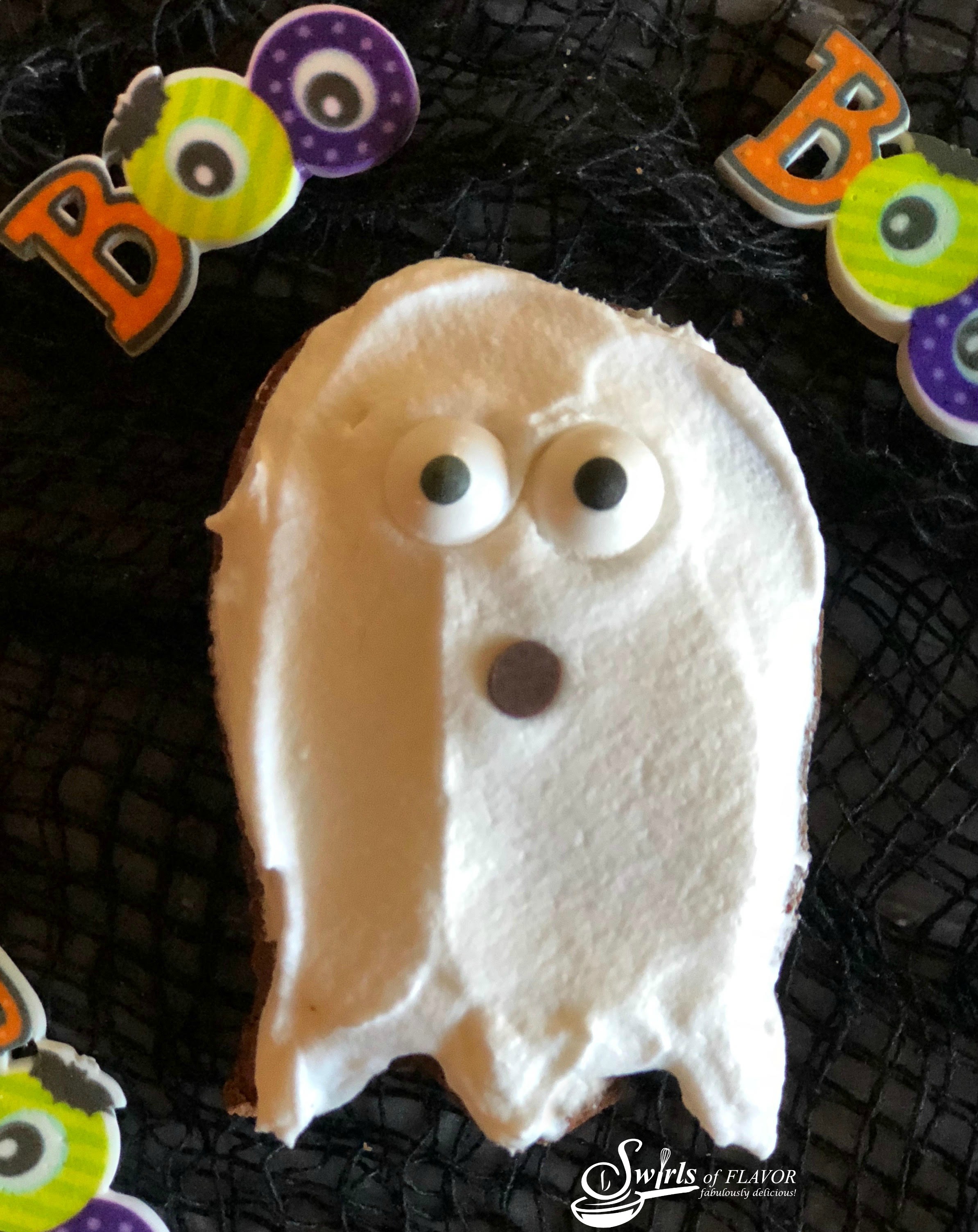 a brownie in the shape of a ghost with sugar eyes and chocolate chip mouth