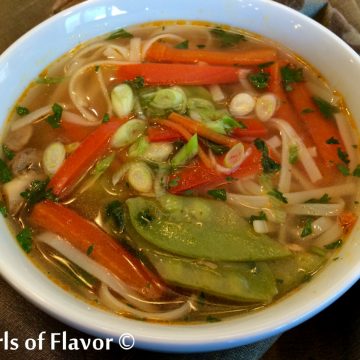 white bowl of Thai ginger soup with fresh vegetables