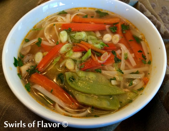 white bowl of Thai ginger soup with fresh vegetables