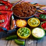 Our Walking Taco Bar is the perfect way to serve up a saucy taco filling and your favorite toppings for the big game. Crush the chips in your bag, top them with a flavorful beef taco filling, pile high with lots of taco toppings, add a plastic fork and you’re all set! #beeftaco #portabletaco #walkingtacobar #tacosinabag #funforkids #gamedayfood #superbowl #easyrecipe #entertaining #swirlsofflavor