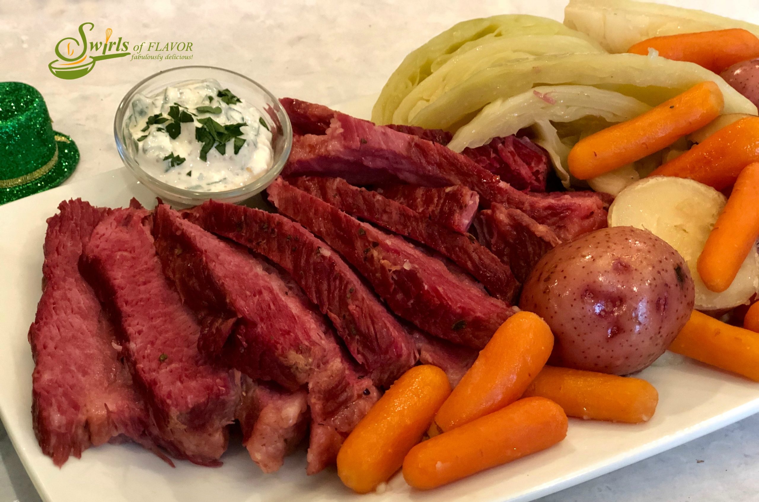 slices of corned beef with cabbage, carrots and potatoes on a white platter with cream sauce