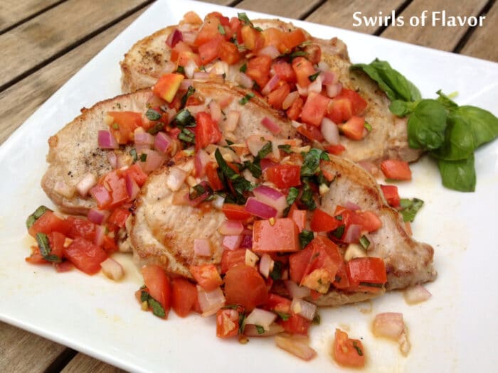 Italian pork chops with tomato topping and fresh basil leaves