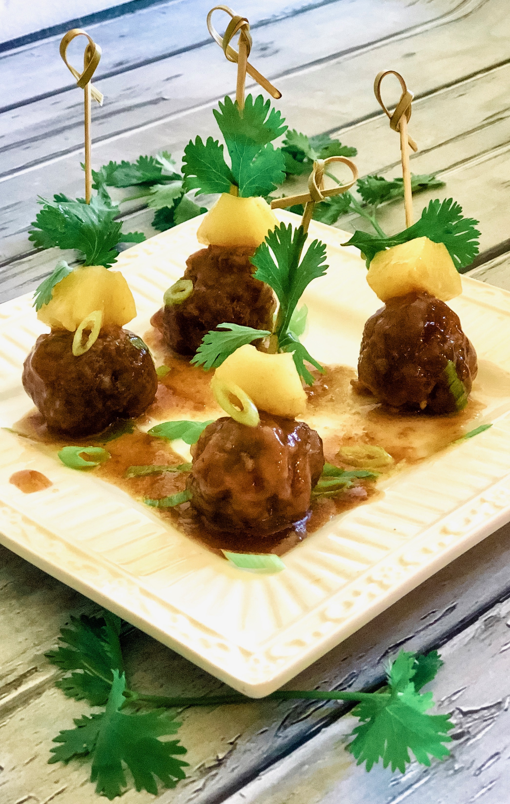 mini meatball appetizers with pineapple chunks and cilantro on skewers