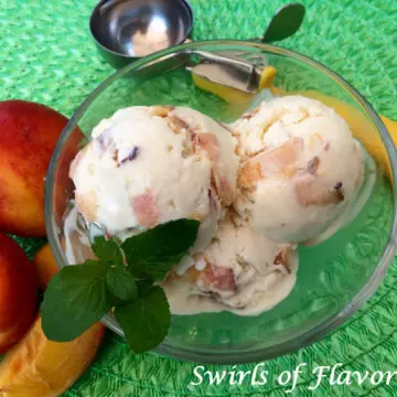 homemade peach ice cream in a clear bowl with fresh mint