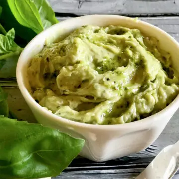 pesto butter in white dish with fresh basil