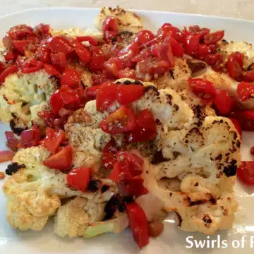 cauliflower steaks with tomatoes on a platter