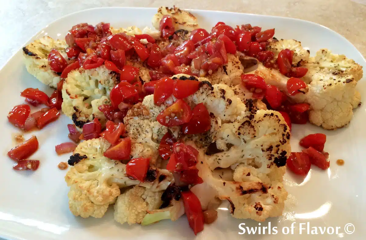 cauliflower steaks with tomatoes on a platter