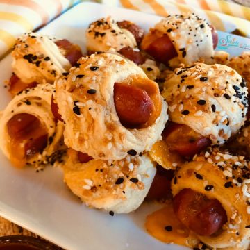 pigs in blankets with cheese on white platter