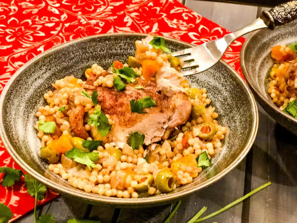 a forkful of chicken over a bowl of chicken with apricots