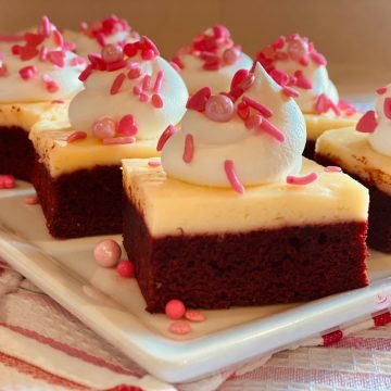 red velvet cheese cake brownies with whipped cream and pink sprinkles
