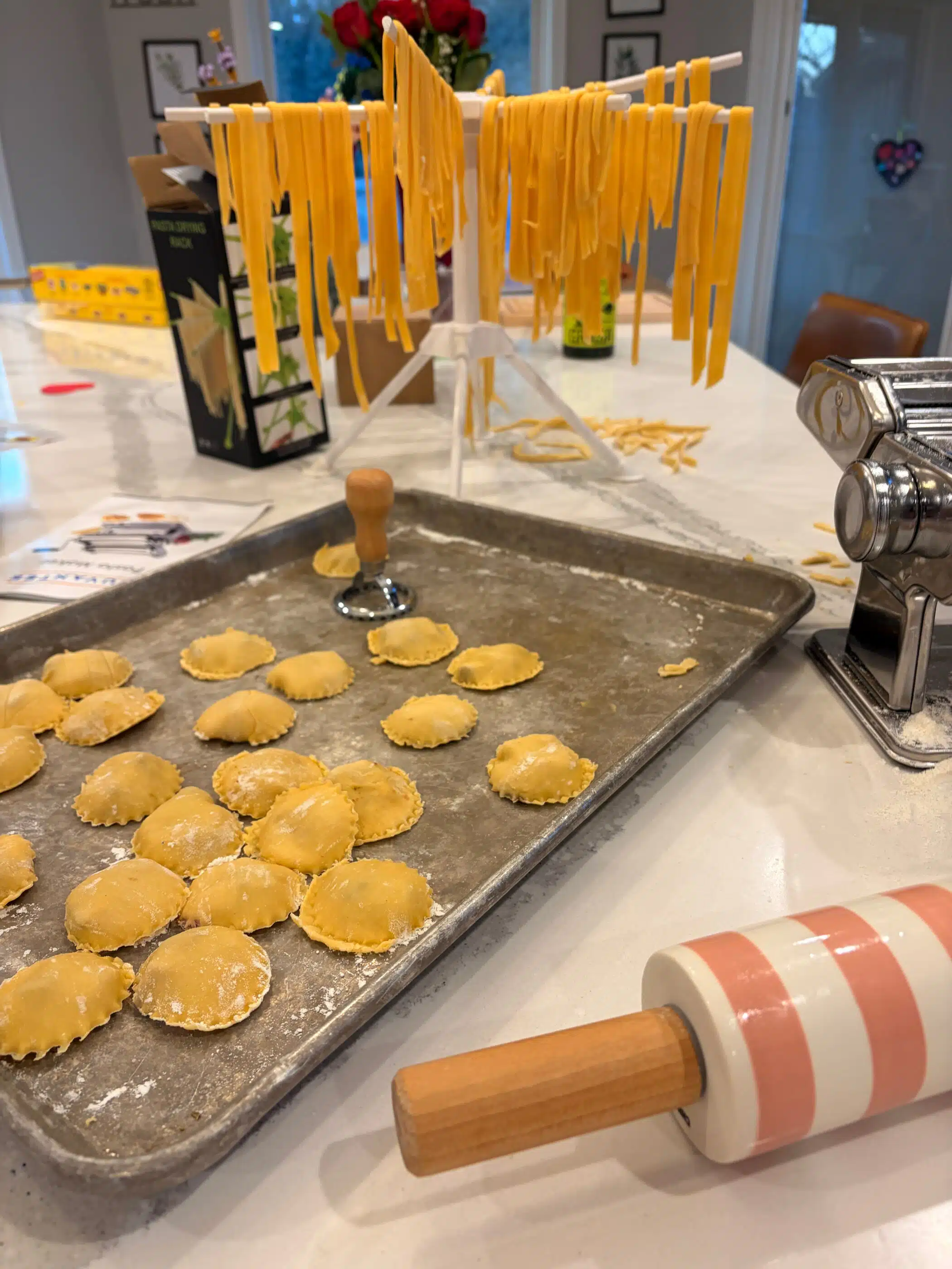 homemade fettuccine on drying rack and homemade ravioli with rolling pin
