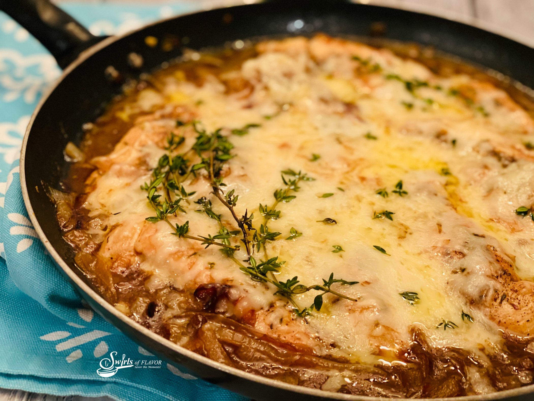 French Onion Chicken recipe in a skillet toped with cheese and fresh thyme